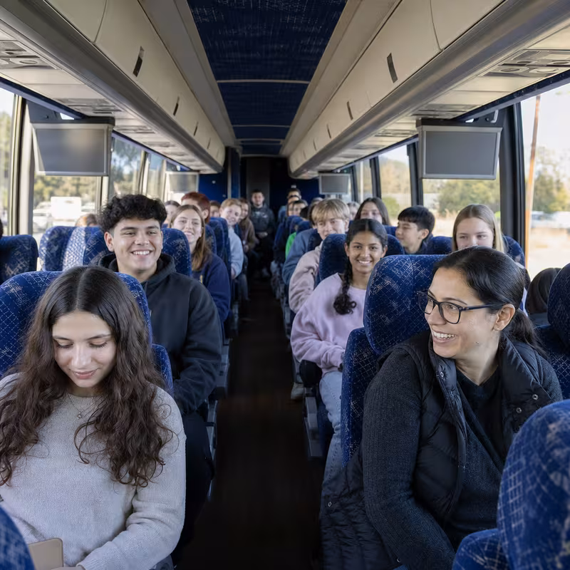 Group boarding a white charter bus for School Transportation transportation in Huntington Beach